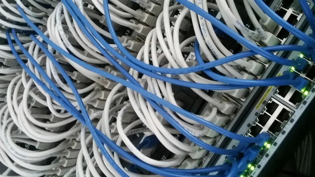 Cabos de rede conectados a switch em rack de cabeamento estruturado